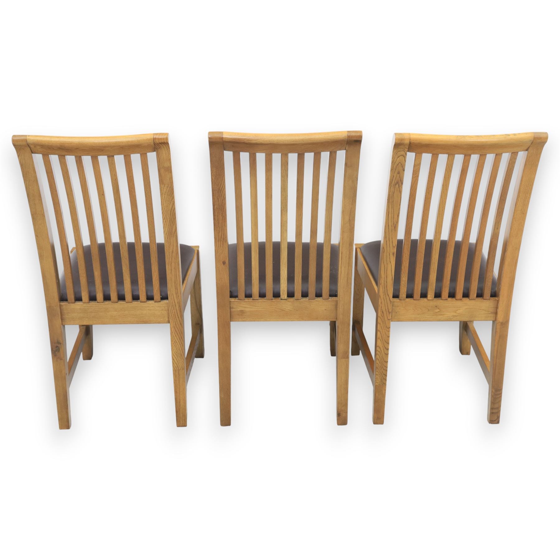 Contemporary oak extending dining table, moulded rectangular top with visible grain and inset extension leaf, pull out extending mechanism, standing on four square legs, accompanied by a set of high slat back chairs with upholstered brown faux leather seats and square tapering supports joined by stretchers