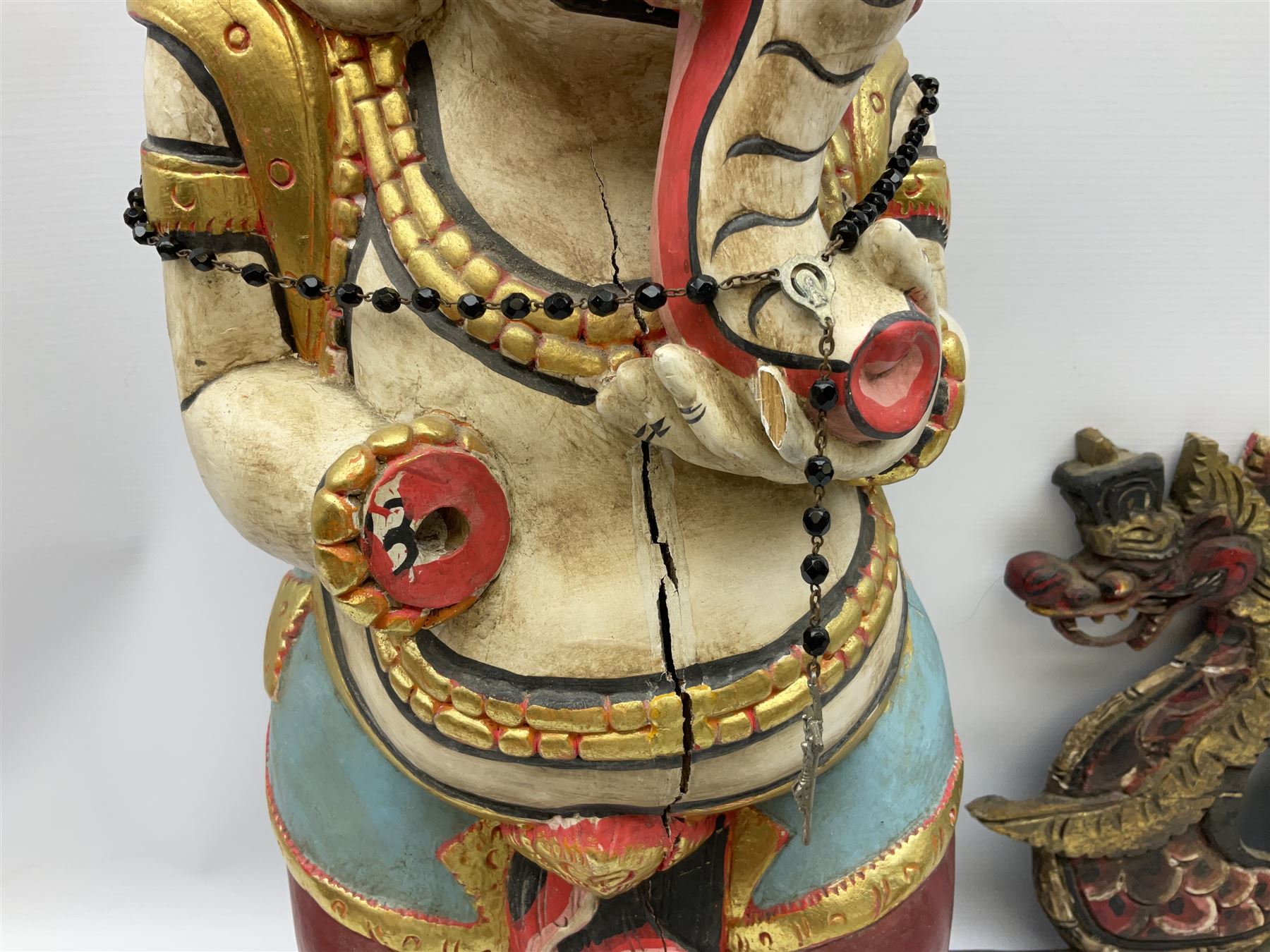 Balinese wood wall panel carved as a dragon boat with passengers, painted in reds and greens with gilding, together with a carved wood figure of Ganesh Deity decorated with gilt, raised upon circular lotus flower plinth, H78cm