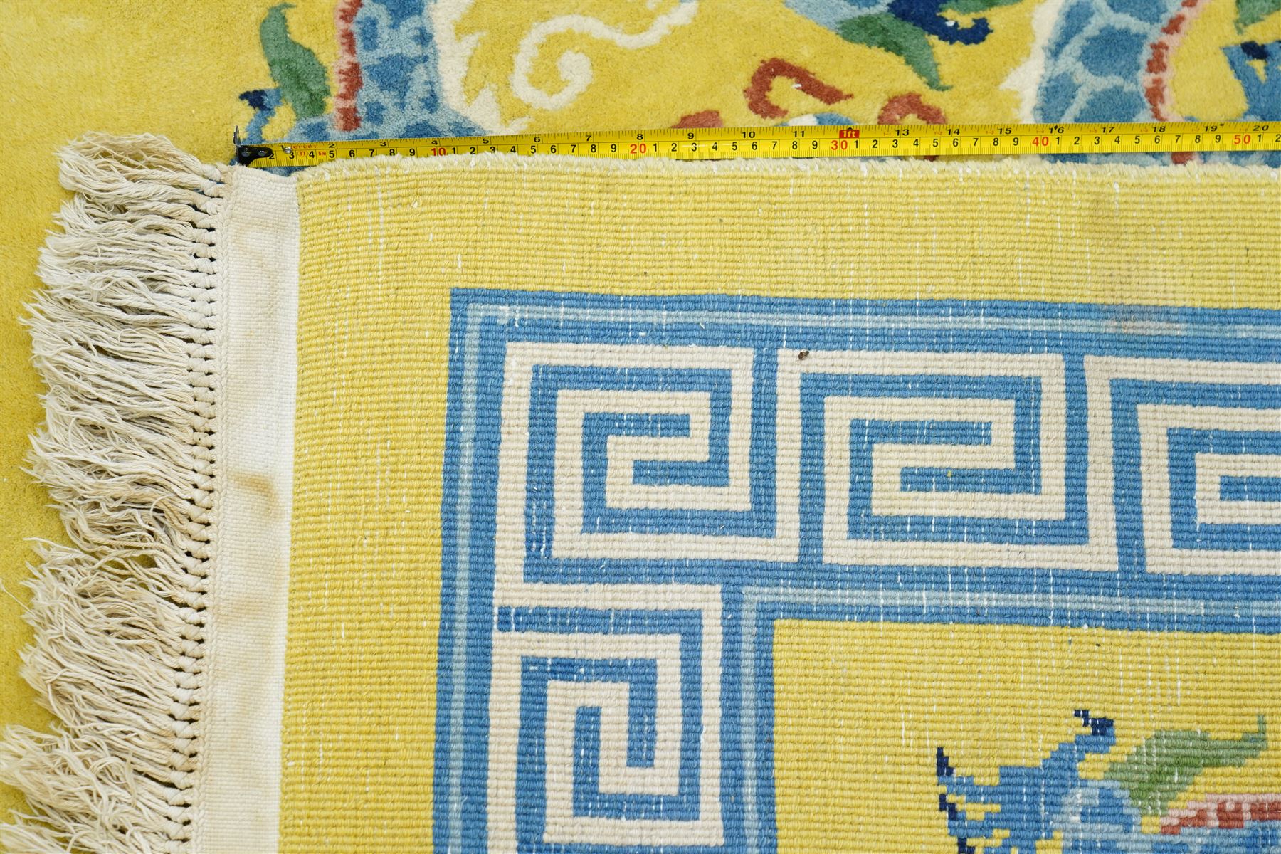 Modern Chinese hand-knotted wool pile carpet, golden field decorated with conforming dragons amidst stylized cloud scrolls enclosed by a Greek gey meander border, with cotton fringe ends 