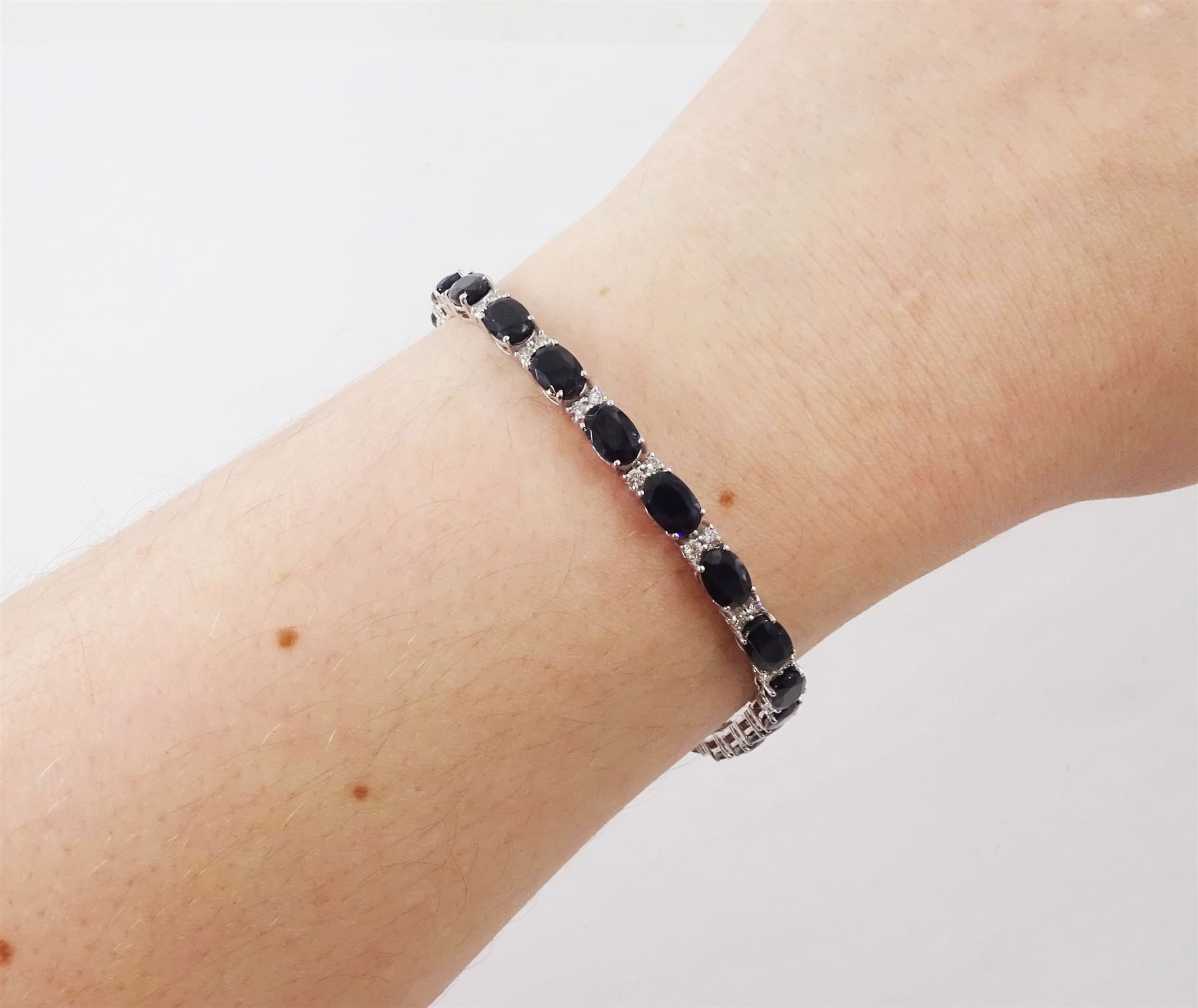 18ct white gold sapphire and diamond bracelet, twenty-three oval cut sapphires, each spaced by two round brilliant cut diamonds, stamped 750, total sapphire weight 14.785 carat, total diamond weight 0.88 carat