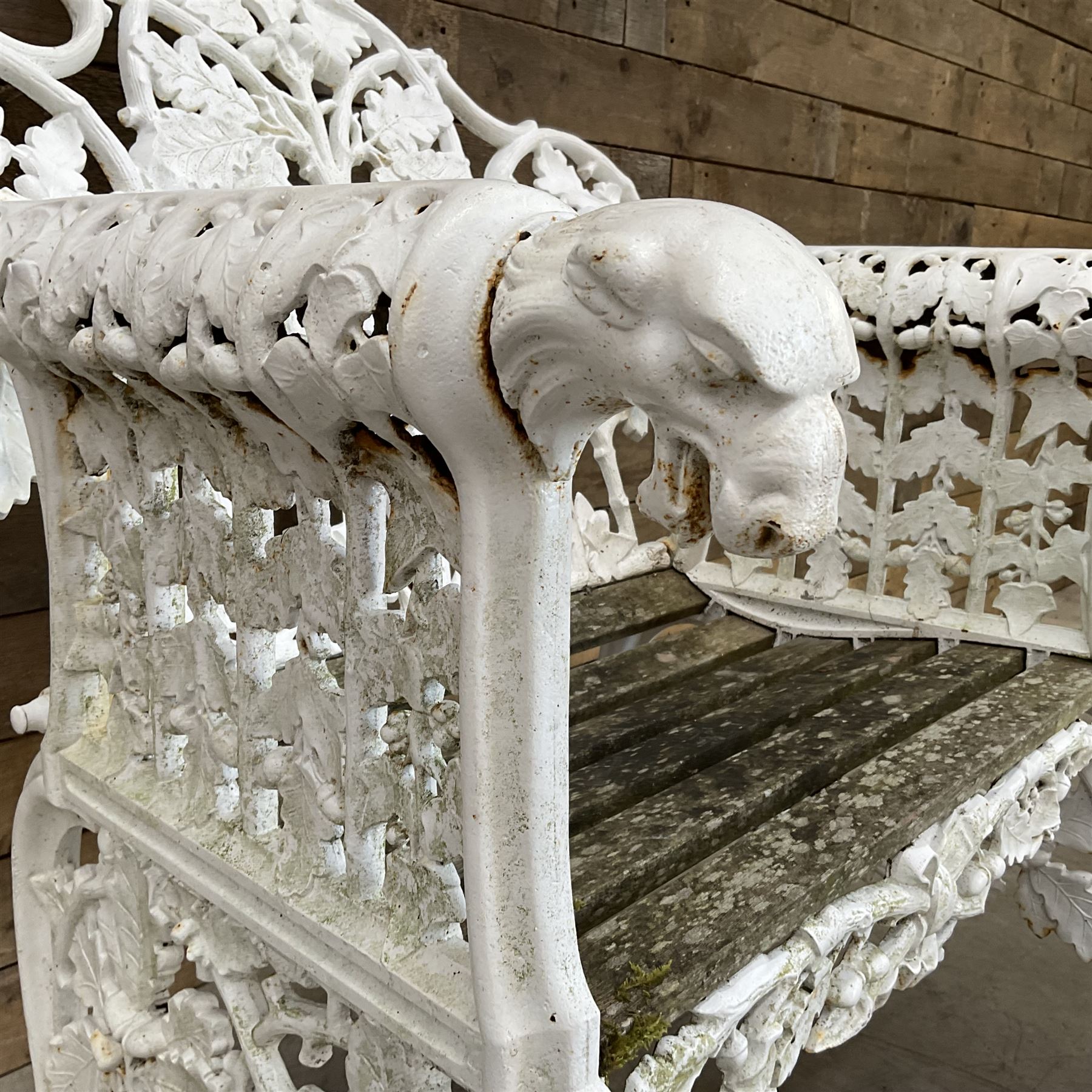 20th century Coalbrookdale design cast iron oak leaf and acorn armchair, white painted cast iron frame with slatted wooden seat, the pierced and shaped back decorated with scrolling oak branches and leafage, flanked by dog mask arm terminals over cabriole supports with paw feet