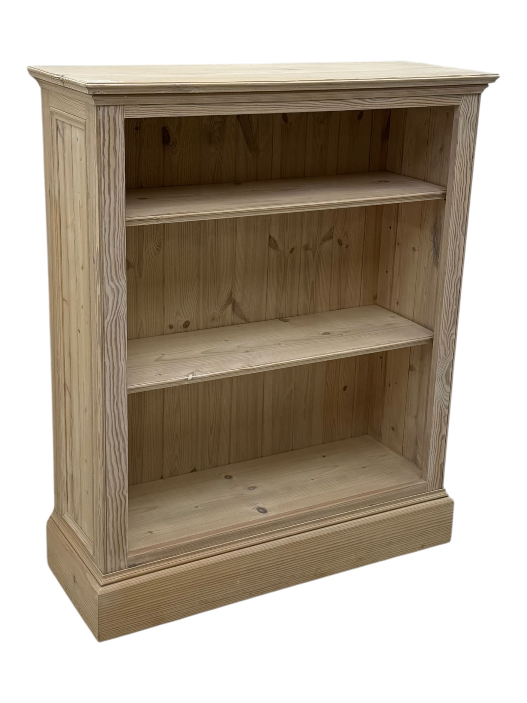 Contemporary light pine open bookcase, rectangular top with stepped moulded edge above a boarded back, fitted with two adjustable shelves, on a plinth base