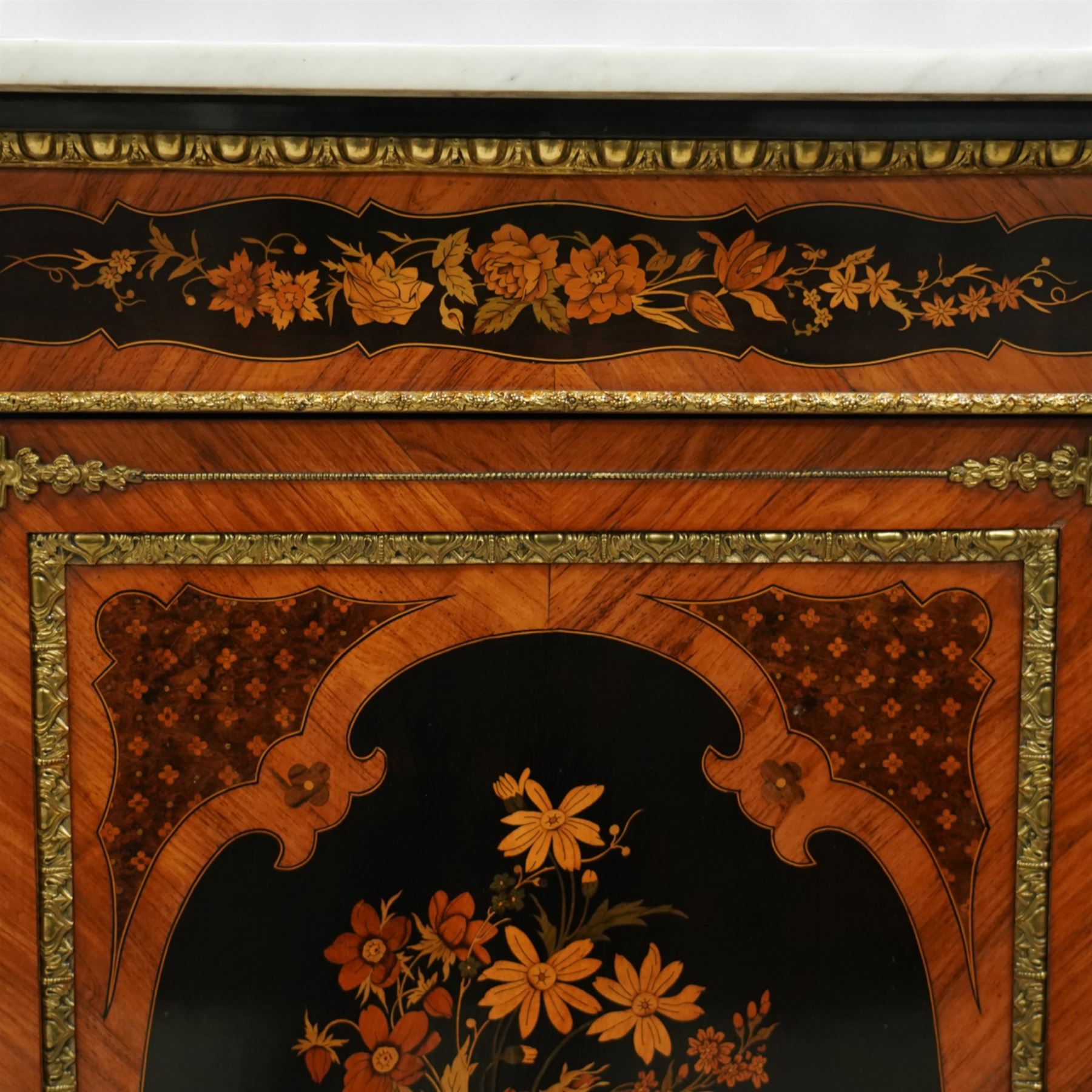 Late Victorian floral marquetry and ormolu mounted side cabinet, with white marble top above a frieze of floral inlay, single cupboard door revealing a shelved interior, with central floral bouquet panel within gilt-bronze border, flanked by gilt metal mounts of female masks and scrolls, on shaped plinth base