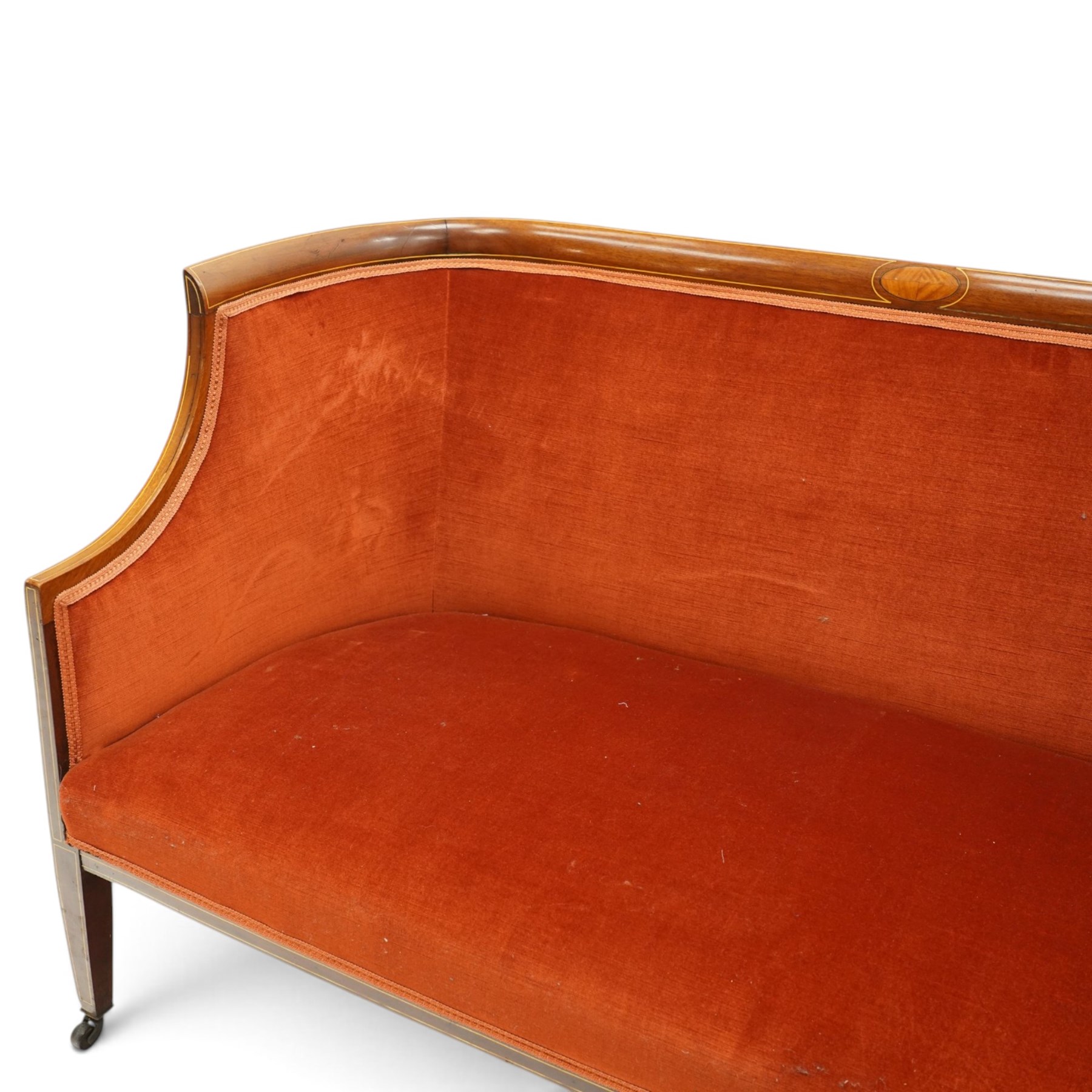 Edwardian inlaid mahogany tub two seater settee, traditional shape with satinwood stringing, upholstered in crimson fabric with sprung seat, on square tapering supports with castors