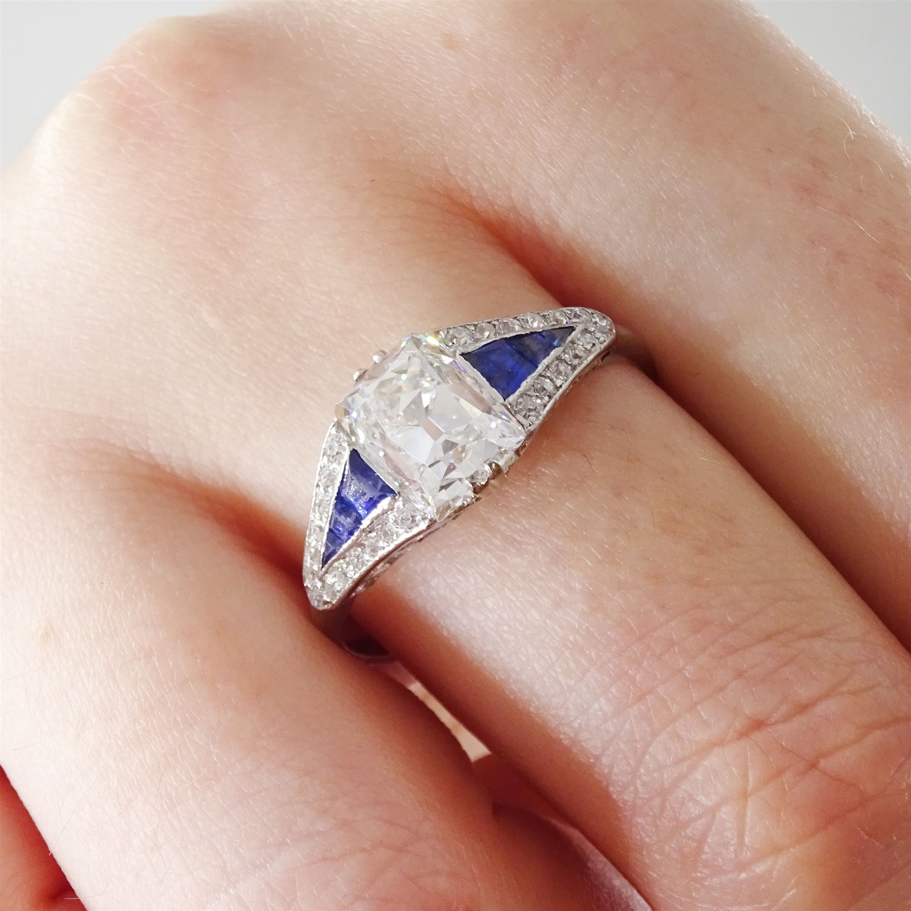 Platinum diamond and sapphire ring, the principal old cushion cut diamond of approx 1.50 carat, each side set with three graduating calibre cut sapphires and old cut diamond surround