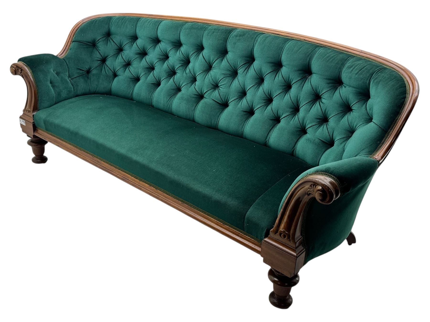 Victorian mahogany settee, upholstered in green buttoned fabric, moulded frame and scroll carved arm terminals, turned supports on castors