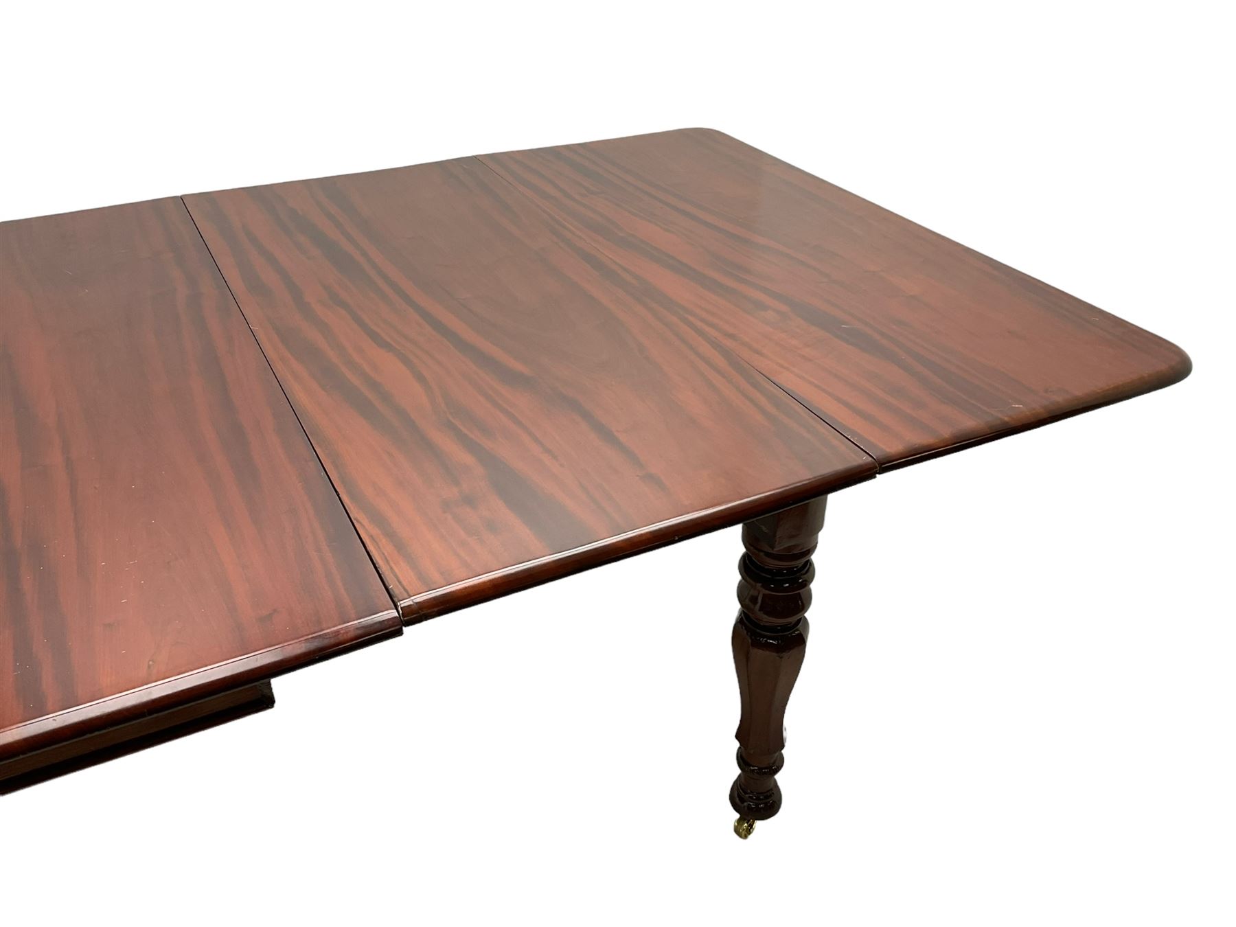19th century mahogany extending dining table with three additional leaves, rectangular top with rounded corners, pull-out action, on turned and faceted supports with brass castors