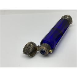 Late Victorian silver mounted ruby glass cylindrical scent bottle, with interior glass stopper, Birmingham 1900, makers mark worn, H8cm, together with a Victorian double ended cut blue glass perfume bottle mounted with white metal screw and flip caps decorated with foliate repousse detailing, H13.5cm