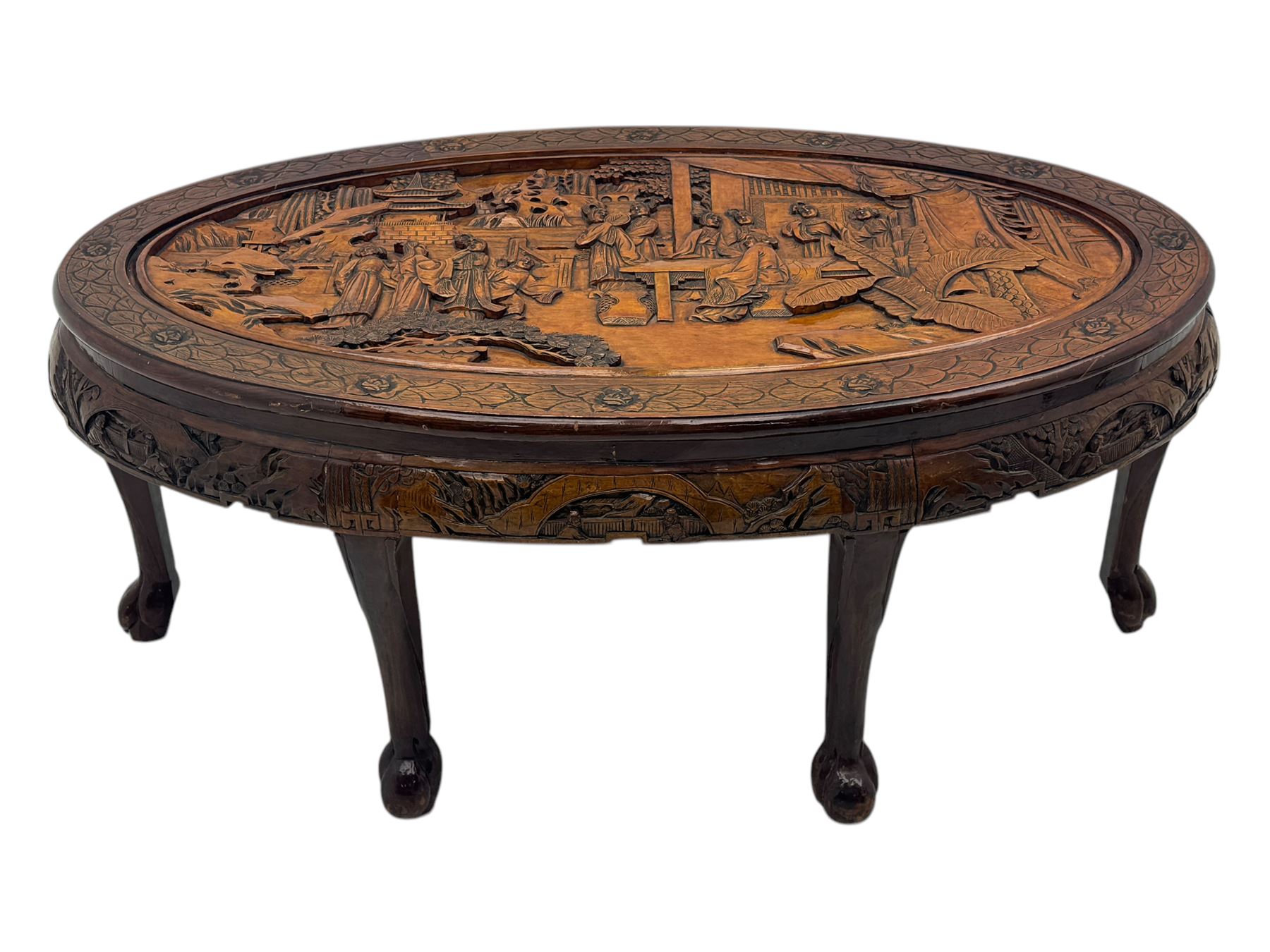 Early 20th century Chinese hardwood nesting coffee table, oval top carved with figures and traditional pagoda scenes with carved frieze, complete with six inset stools or side tables, raised on tapering supports with paw feet