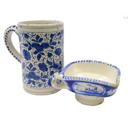 19th century Delft sauceboat, square form, painted with buildings in a landscape, L16cm and 18th/ 19th century Delft tankard decorated with floral sprigs, H16cm (2)  