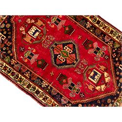 Turkish red ground rug, the three central geometric medallions within indigo spandrels, ivory border with repeating stylised plant motifs
