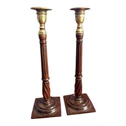 Pair of George III candlesticks, the brass sockets upon fluted and wrythen turned stems, and square weighted bases with turned roundels, H37cm