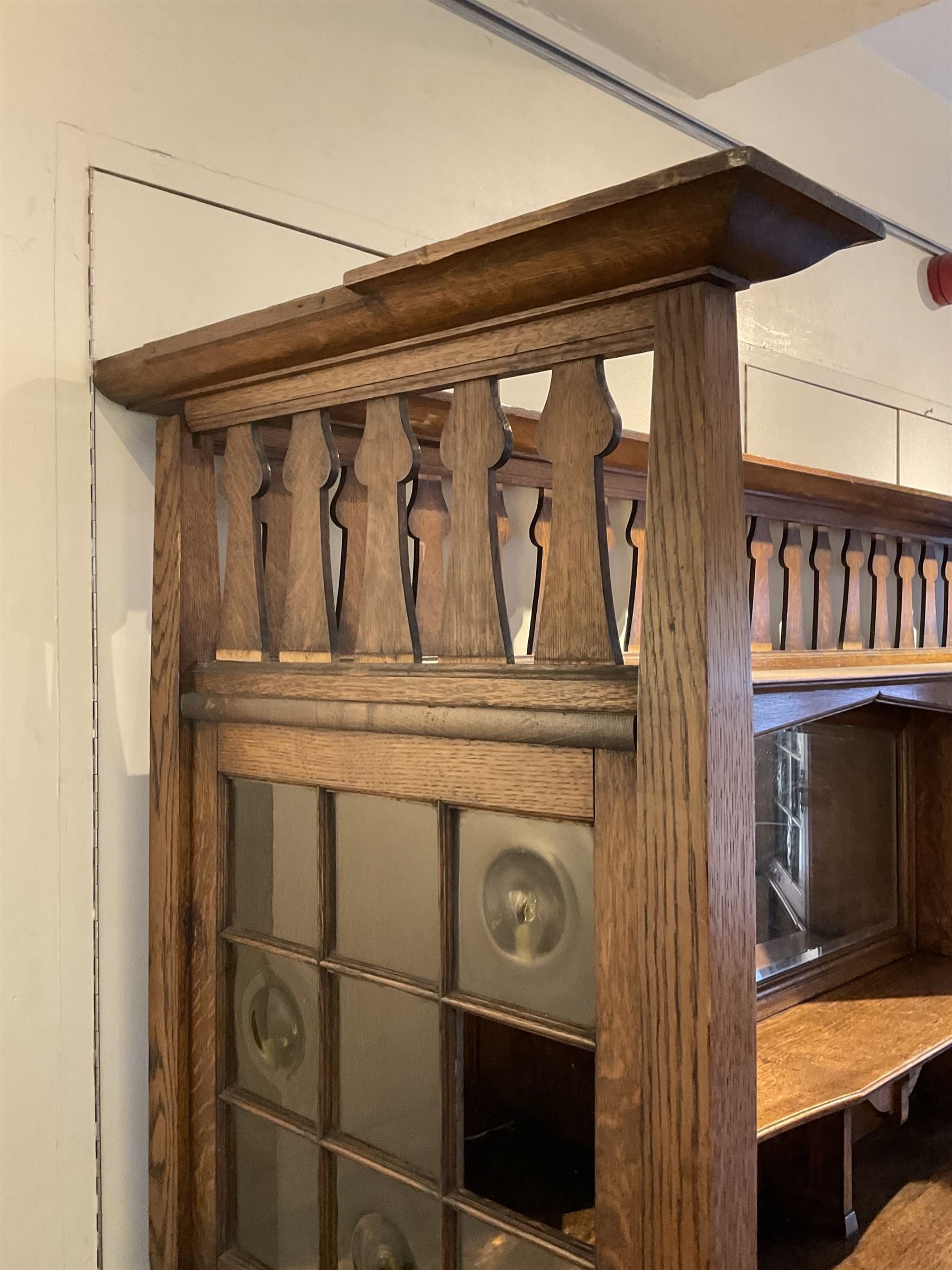 Shapland and Petter - Arts & Crafts period oak dresser, raised gallery top with spade balustrade, central bevelled mirror flanked by two cabinet, astragal glazed doors with yellow tinted glass and bullseye panes, the sides with pierced heart shaped decoration, fitted with two drawers and two double cupboards, enclosed by linenfold panelled doors,  copper work strap hinges and fixtures, on shaped spade feet, the locks stamped 'S&P'