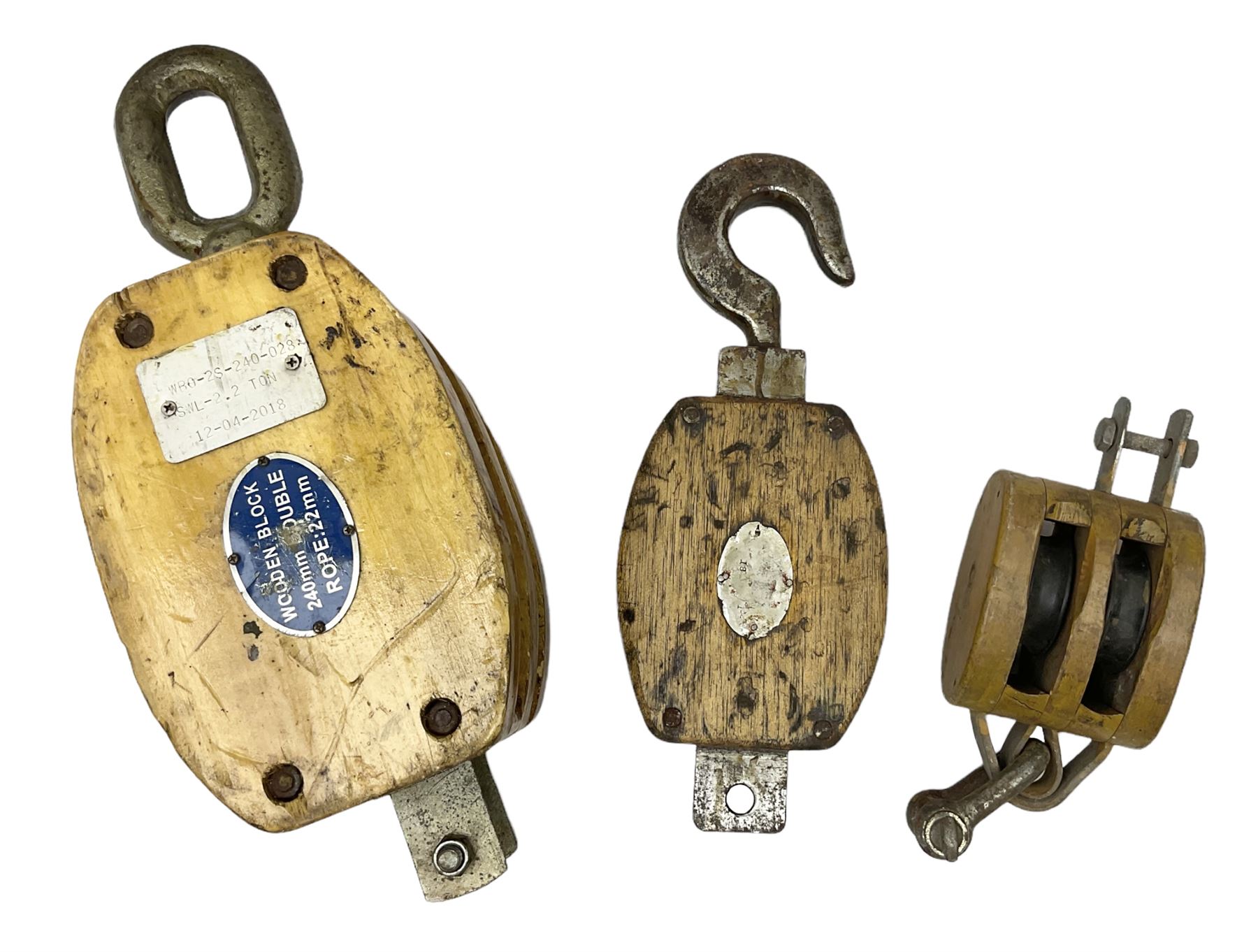 Three ship pulleys comprising wooden block double with swivel eye marked 'wooden block 240mm double rope: 22mm',  wooden block double with upset shackle and wooden block with stiff swivel hook, largest example L50cm