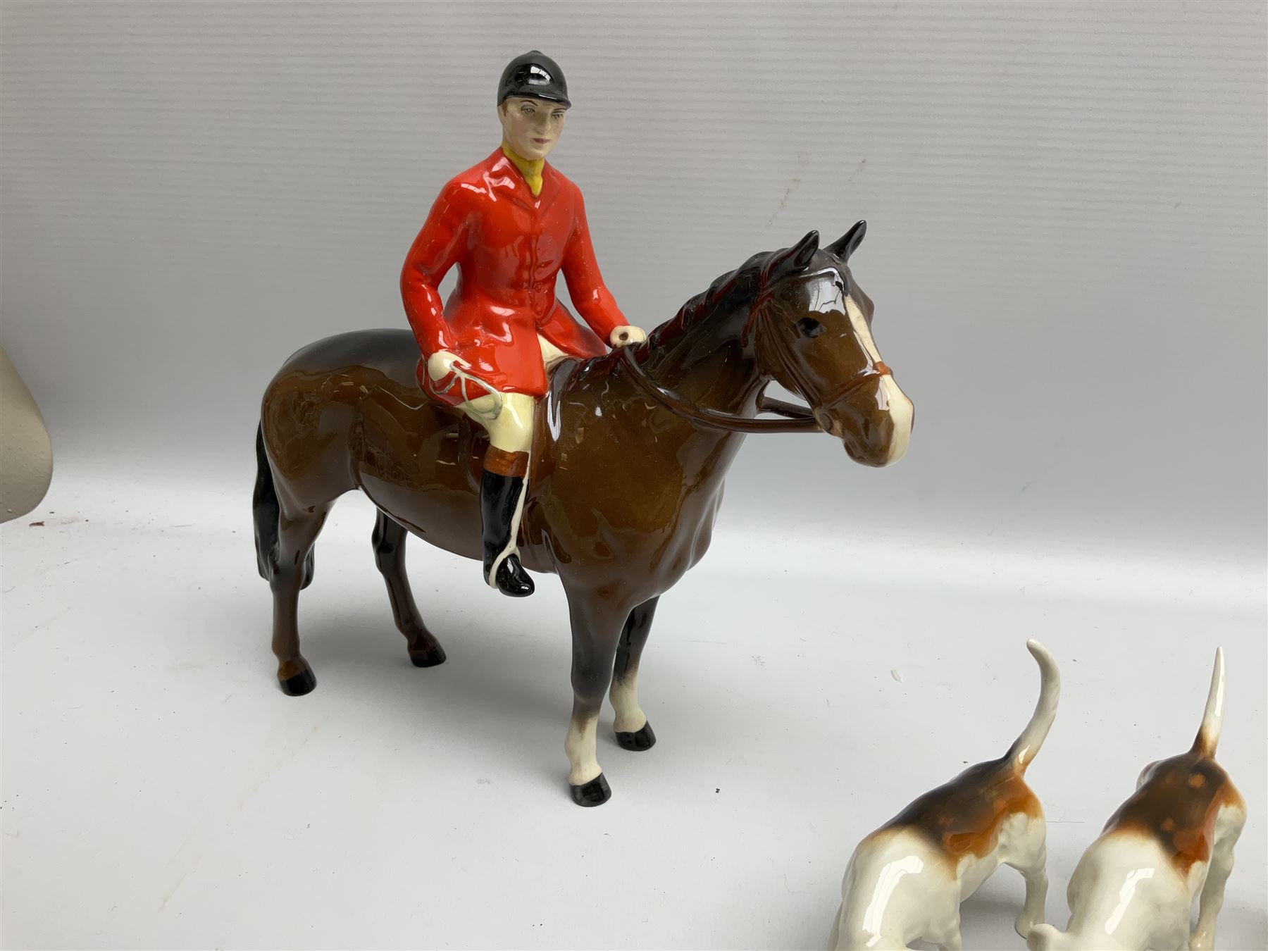 Beswick hunting group, comprising huntswoman on grey horse no 1730, huntsman on brown horse no 1501, two seated fox figures no 1748 and seven fox hounds, all with printed marks beneath (11)