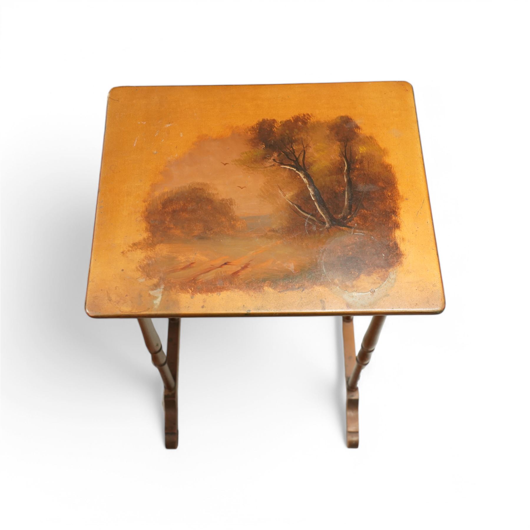 French 19th century painted nest of tables, the largest depicting a romantic scene of courting lovers by a swan lake, indistinctly signed L Desi**, the smaller tables painted with rural landscapes, the painted rectangular tops raised on ring turned end supports united by stretcher