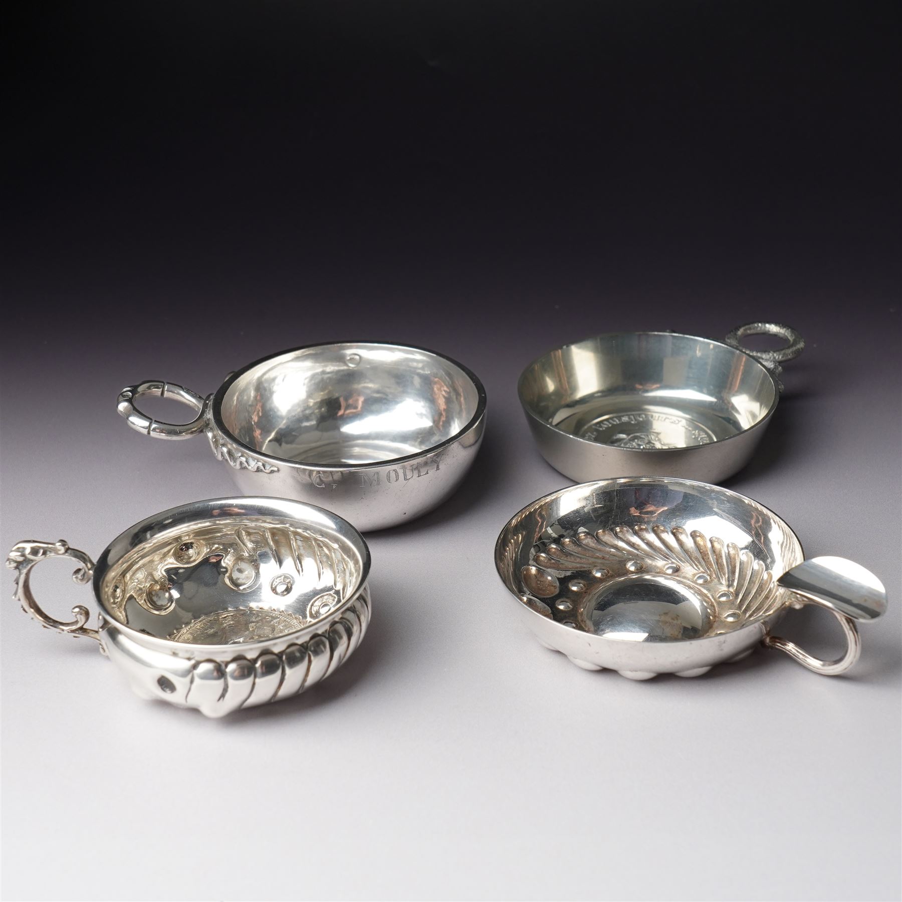 French silver tasse de vin with Minerva's head and makers mark J.P. with an anchor, the rim engraved C Mouly, Spanish tasse de vin inset with a silver coin and two other tasse de vin (4)