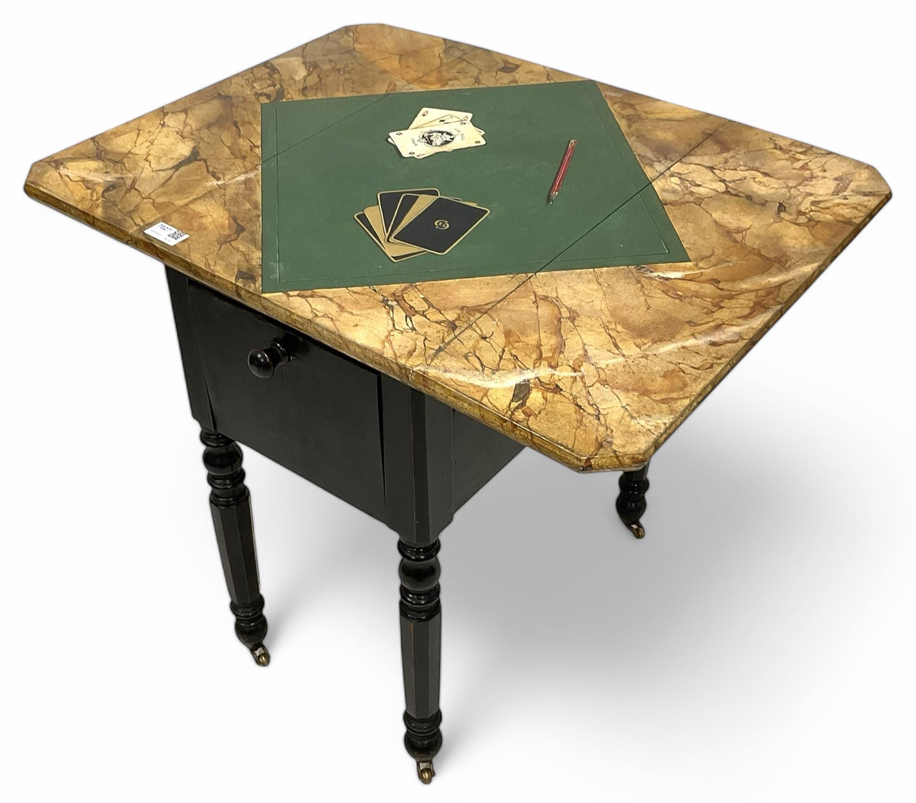 Victorian ebonised drop-leaf pot cupboard with later trompe l'oeil painted top, depicting marbled surface with baize cloth, playing cards and pencil, fitted with two drawers to one end and cupboard to the other with marble inset, on turned and faceted supports with brass castors
