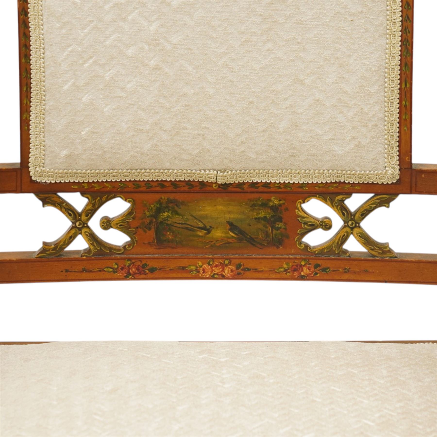 Pair of Victorian Sheraton Revival painted satinwood armchairs, the cresting rail painted with trailing floral bouquets flanked by illusion arcade motifs, over a cameo back and sides with acanthus painted swell-turned uprights, the lower back rail decorated with a bird scene and flanking pierced foliate design, upholstered in ivory fabric, raised on turned supports with further acanthus leaf paintwork, terminating to brass castors