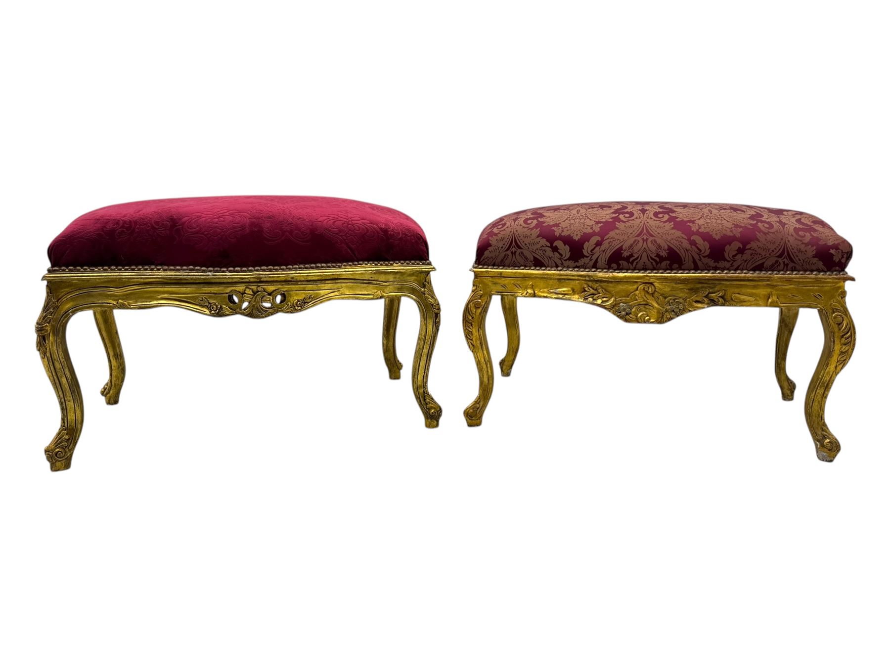 Pair of Louis XV-design giltwood stools, each upholstered in red damask fabric with slight variations in patterns, the carved frames adorned with scrolling foliage and shell motifs, raised on cabriole supports