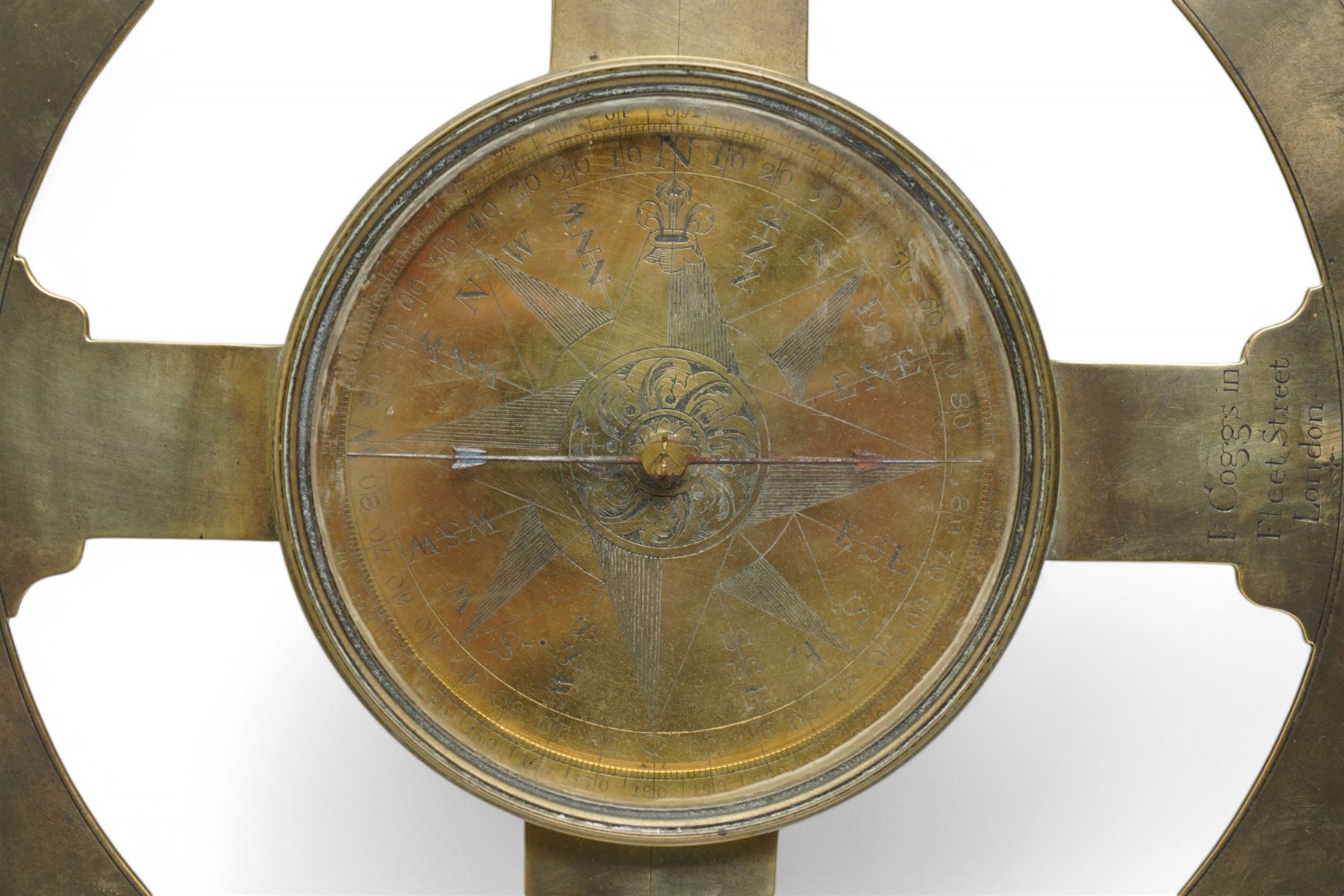 Ihon (John) Coggs of Fleet Street, London,- George II brass circumferentor (theodolite) c1730, housing a cylindrical glazed compass with a steel  indicating hand and engraved (formerly silvered) eight point compass rose to the centre, outer track divided into two-degree intervals and a subsidiary Arabic numeral chapter ring divided into ten minute intervals, mounted on a 12