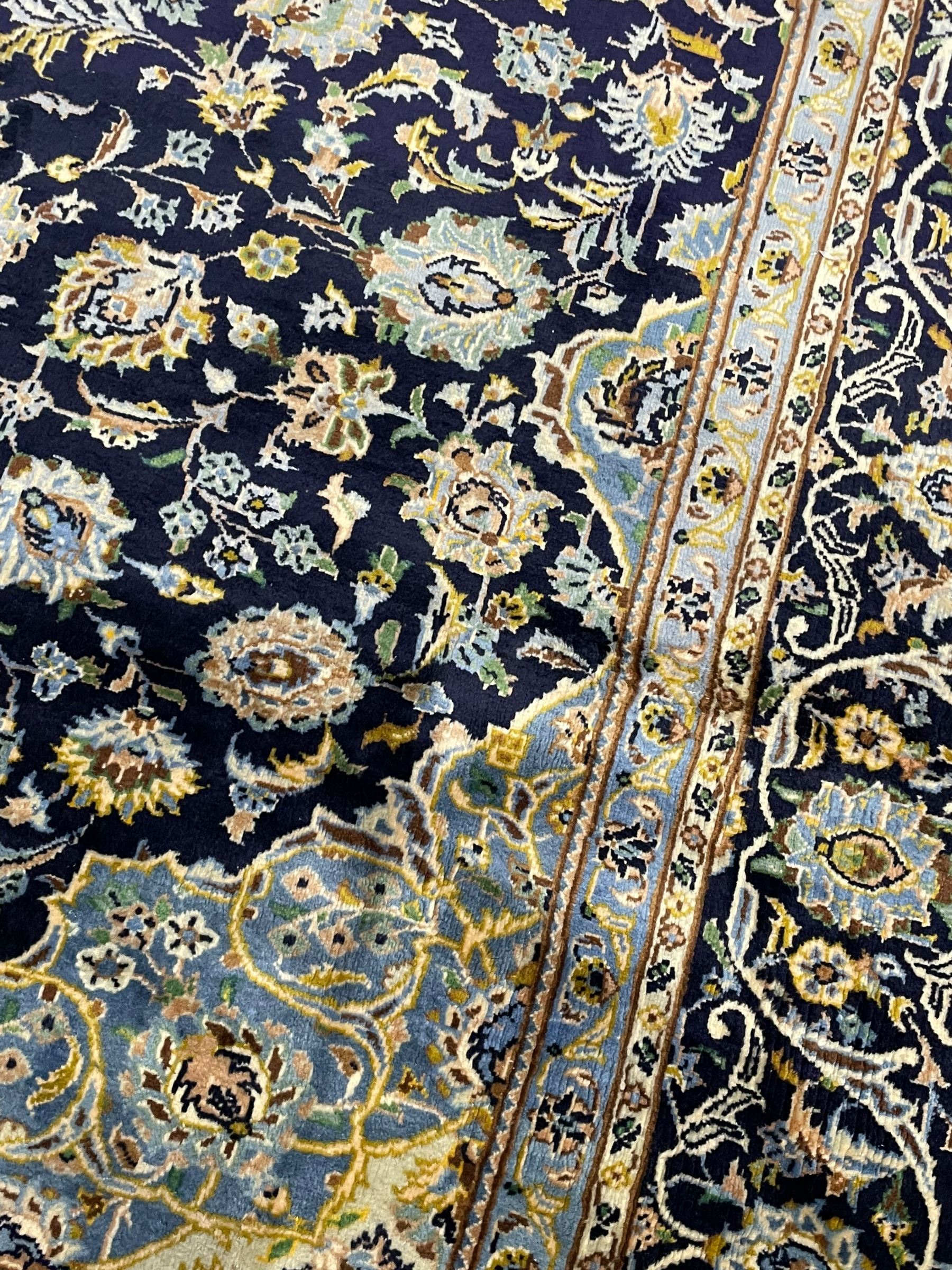 Persian Kashan indigo ground rug, central floral pattern pole medallion, the field decorated with palmettes united by trailing branches, repeating floral pattern border within guard stripes