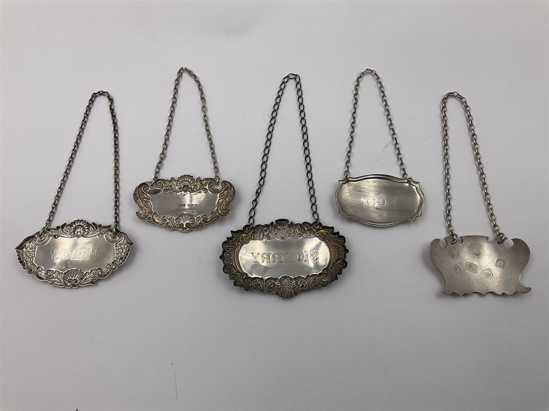 Five modern silver decanter labels, to include two sherry examples, embossed with scrolls and fruits, hallmarked W I Broadway & Co, Birmingham 1991 & 1997, a similar claret example, hallmarked S J Rose & Son, Birmingham 1973, and two plain shaped port and burgundy examples, hallmarked C Robathan & Son, Birmingham 1997 and A Haviland-Nye, London 1968