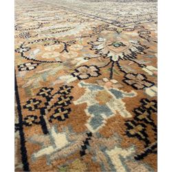Large Persian indigo ground rug, the busy field decorated with trailing branches and flower heads, peach border decorated with palmettes -