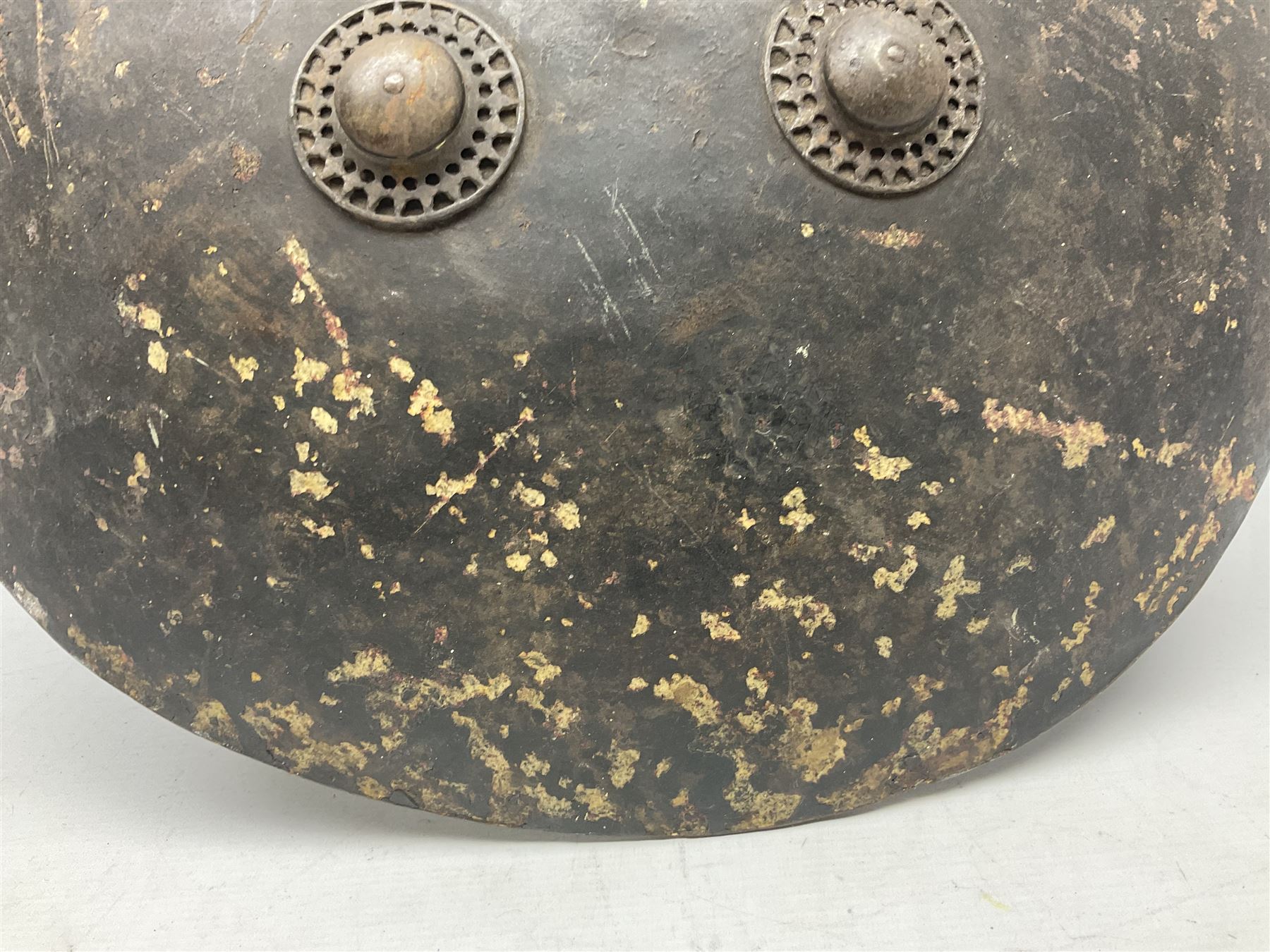 Indian black lacquered hide shield/dhal, of circular convex form fitted at its centre with four pierced iron bosses, each of hemispherical form with wide brims, the bosses corresponding on the inside with four iron rings for enarmes D53.5cm