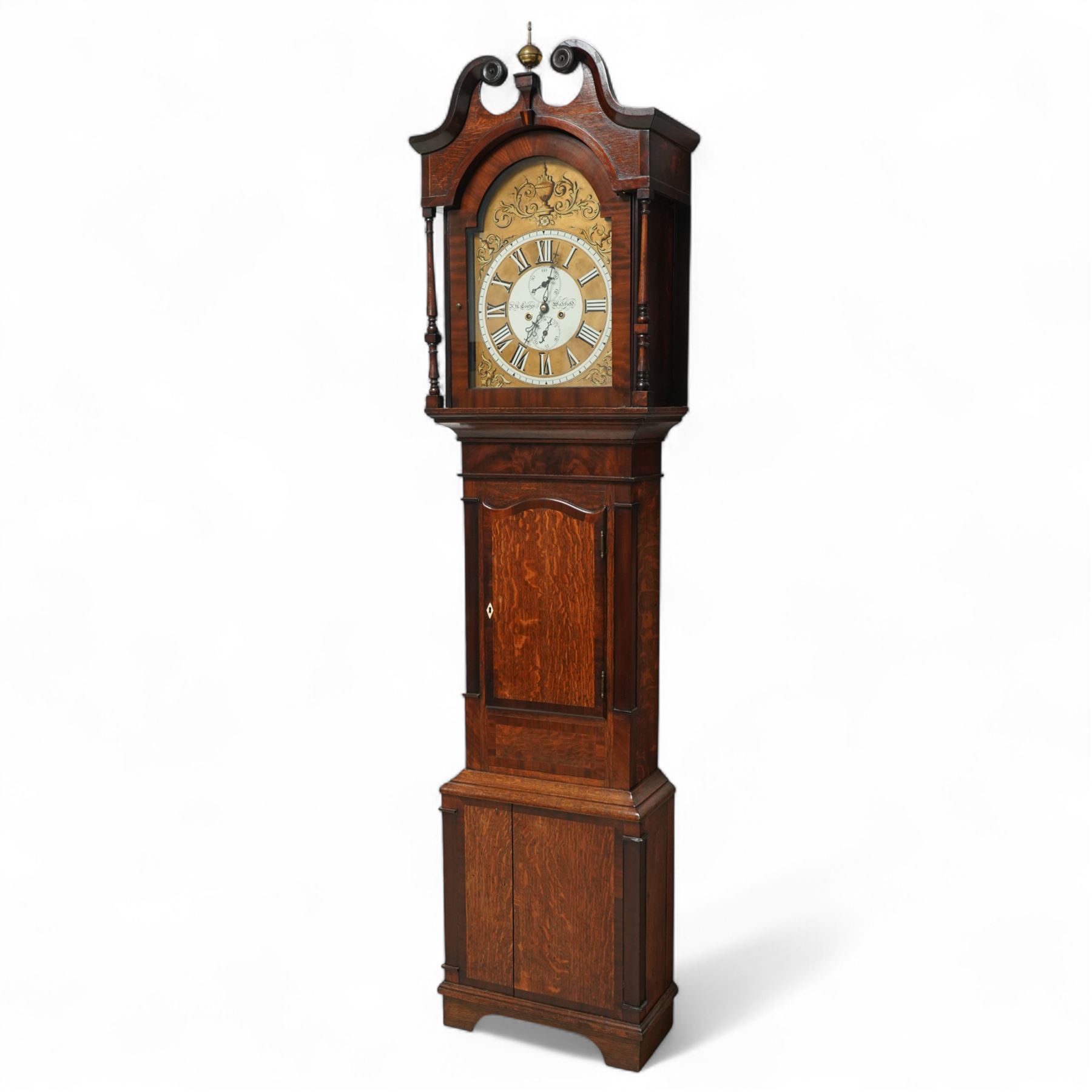 John Henry Coates of Wakefield- late19th century oak and mahogany 8-day longcase clock c 1860, with a swan necked pediment and central brass ball and spire finial, break arch hood door flanked by unusual spindle turned pilasters, trunk with recessed rectangular corners and a wavy topped door, on a square plinth with conforming recessed corners and raised on a shaped base, fully painted dial with matching decorative rococo painted decoration to the spandrels and arch, with 