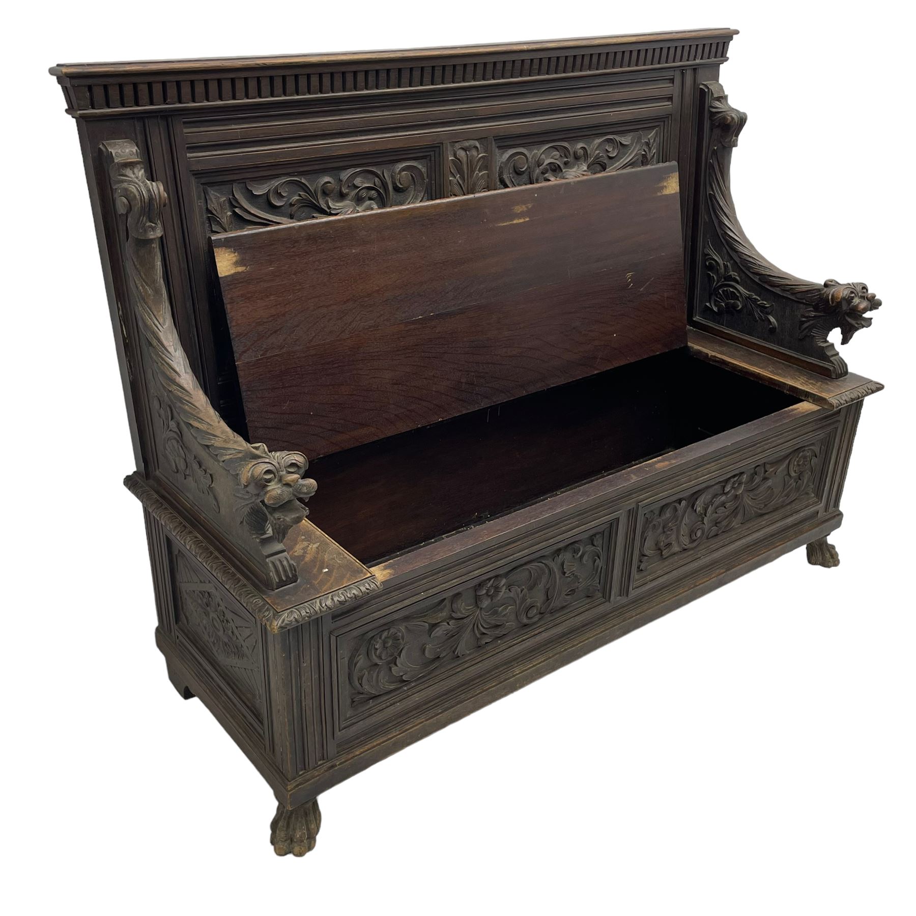 19th century oak hall bench, dentil cresting rail over moulded frame with panelled back carved with fire-breathing mythical beasts and central acanthus leaf motif, scroll carved down-sweeping arms carved with grotesque masks with scrolled foliage and shells, hinged box seat carved with scrolling foliage over panelled front with further carved foliage decoration, on paw carved front feet 