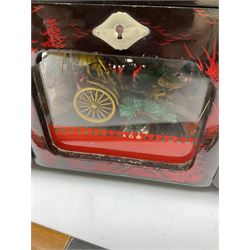 Oriental lacquered jewellery box, the body decorated with a black and red mountainous riverscape enclosing a glass compartment with simulated ivory rickshaw figure and three hinged lids opening to reveal mirror and various compartments and painted ceremonial stick