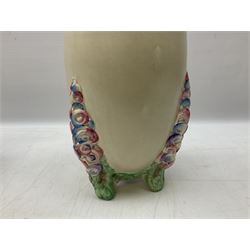 1930s Carlton Ware Art Deco Garden pattern vase of shouldered ovoid form, decorated with blue, pink and yellow flower heads on a mottled blue and white ground, pattern no. 3413, with printed and painted marks beneath, H19cm, together with a Clarice Cliff My Garden pattern vase, raised upon three feet with blue, pink and purple moulded Hollyhock design, H20cm, with Clarice Cliff Wilkinson Ltd England marks beneath