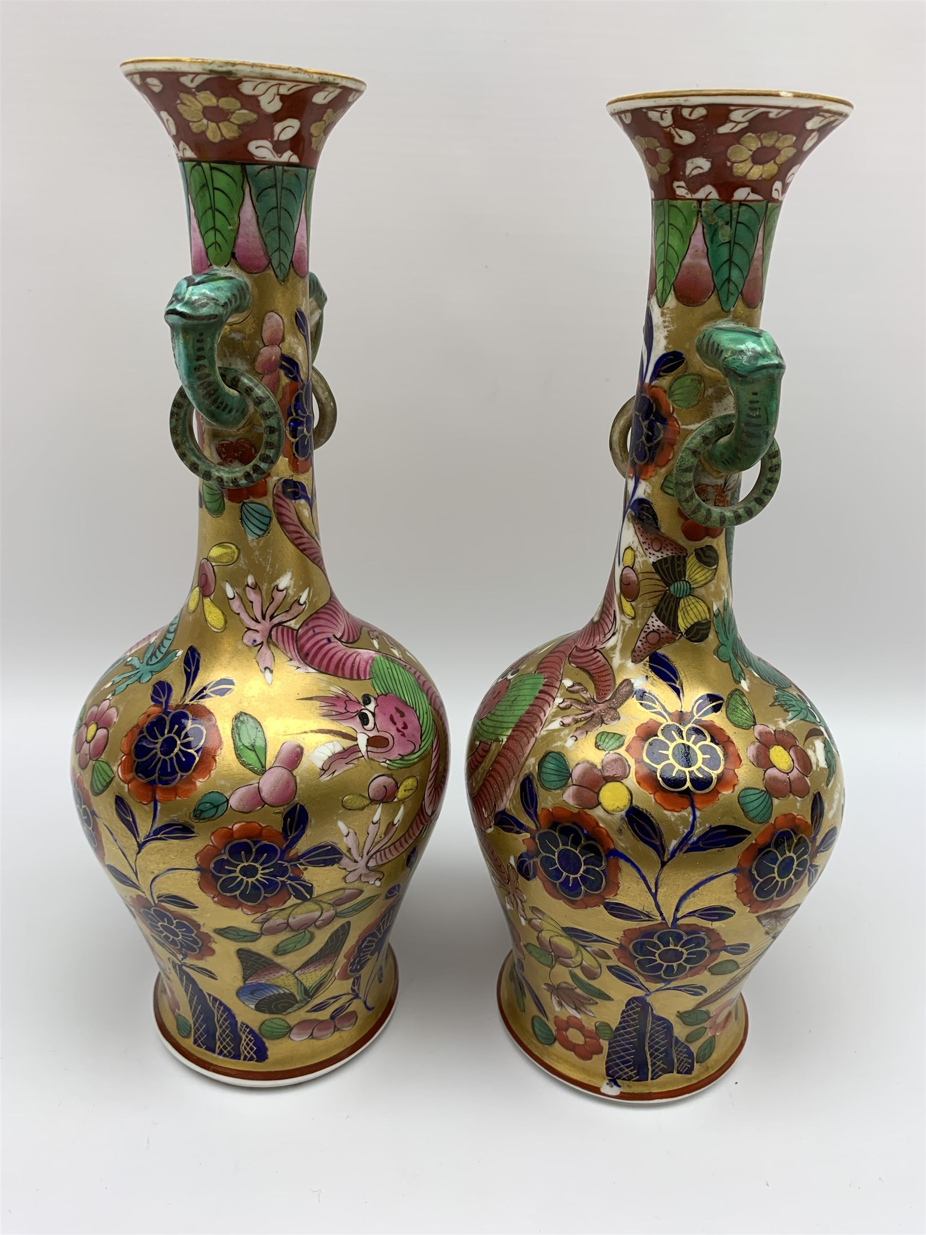 Pair of early 19th century Miles Mason vases, the baluster bodies with tall slender necks supporting twin stylised trunk handles with rings, decorated with Chinese dragons, butterflies, and blossoming flowers against a gilt ground, with spurious Chinese marks beneath in iron red, H27.5cm