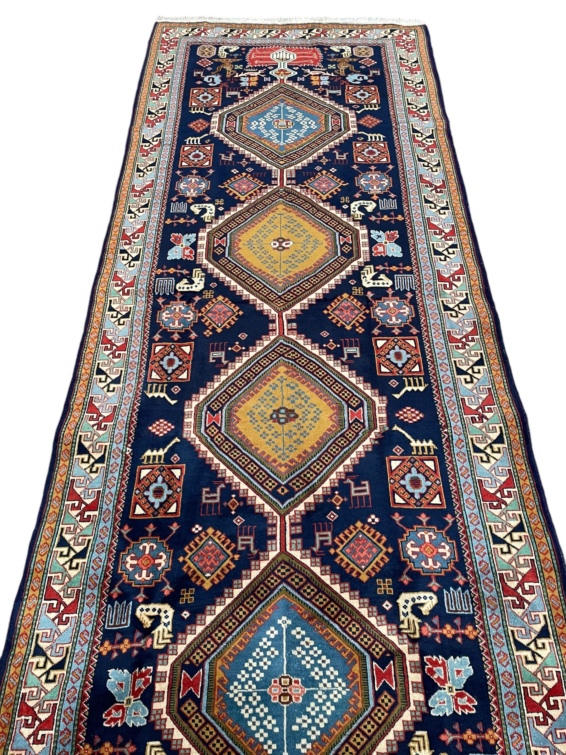 Persian Ardabil indigo ground rug, four interconnected lozenge medallions surrounded by ewer, bird, dragon, camel and geometric motifs, hooked border within guard stripes 