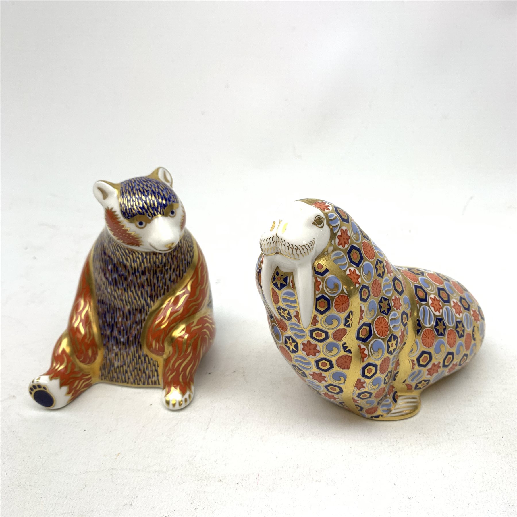 Two Royal Crown Derby paperweights, the first modelled as a Honey Bear, the second as a Walrus, each with print mark beneath, and gold stopper. 