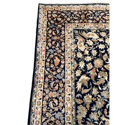 Persian Kashan indigo ground rug, the field consisting of trailing flower head bands and leafy branches, decorated with kuş or bird motifs, the border with repeating border containing curling leaves and flower heads, within guard bands 