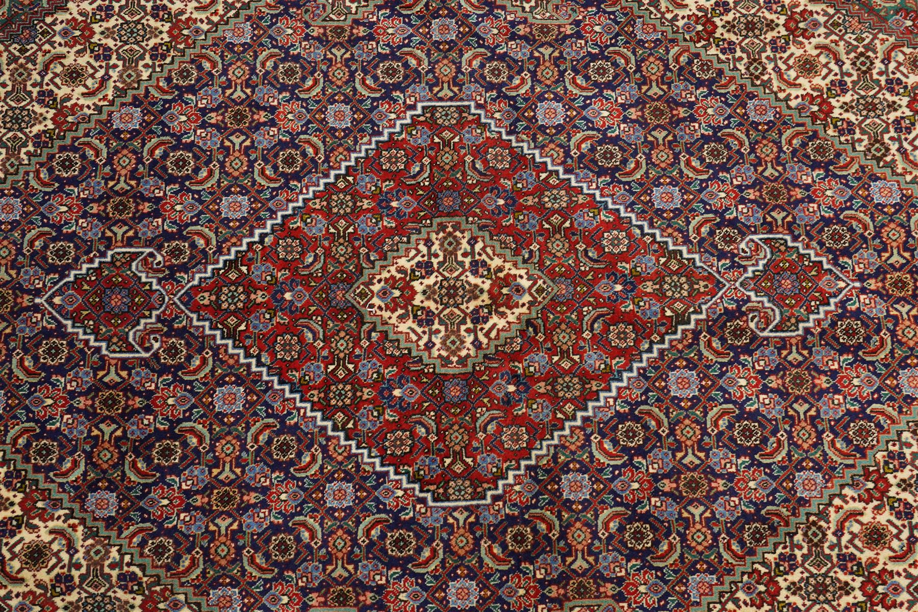 North West Persian Tabriz hand-knotted rug, ivory field with a central lozenge medallion in deep indigo and madder red, enclosing a inner reserve with stylized floral motifs, spandrels with angular floral sprays, main border of repeating floral vinery and palmettes, framed by multiple guard borders, with cotton fringe ends