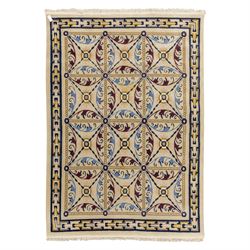 Rugs by Design - Nepalese wool rug, cream field decorated with repeating diamond trellis enclosing scrolling foliate motifs in blue, burgundy and ochre, within chain-link border and fringed ends