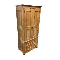 Traditional pine double wardrobe, fitted with two panelled doors enclosing sliding trays over three drawers, flanked by fluted uprights