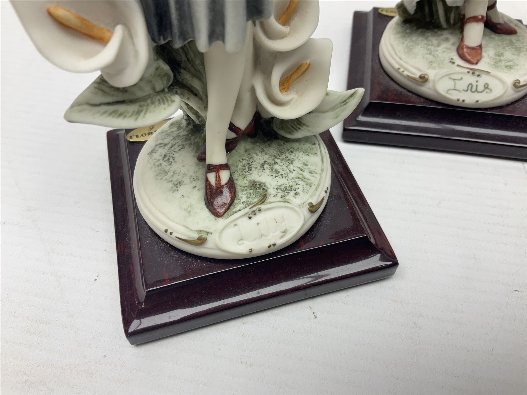 Set of four Giuseppe Armani Florence figures, Iris, Rose, Lily and Daisy, each modelled as ladies in 1920s dress amongst flowers, with names and signature inscribed and upon mahogany base, H23cm