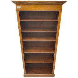 Edwardian inlaid mahogany open bookcase, projecting dentil cornice over crossbanded frieze, fitted with four adjustable shelves with reeded facias, on skirted base