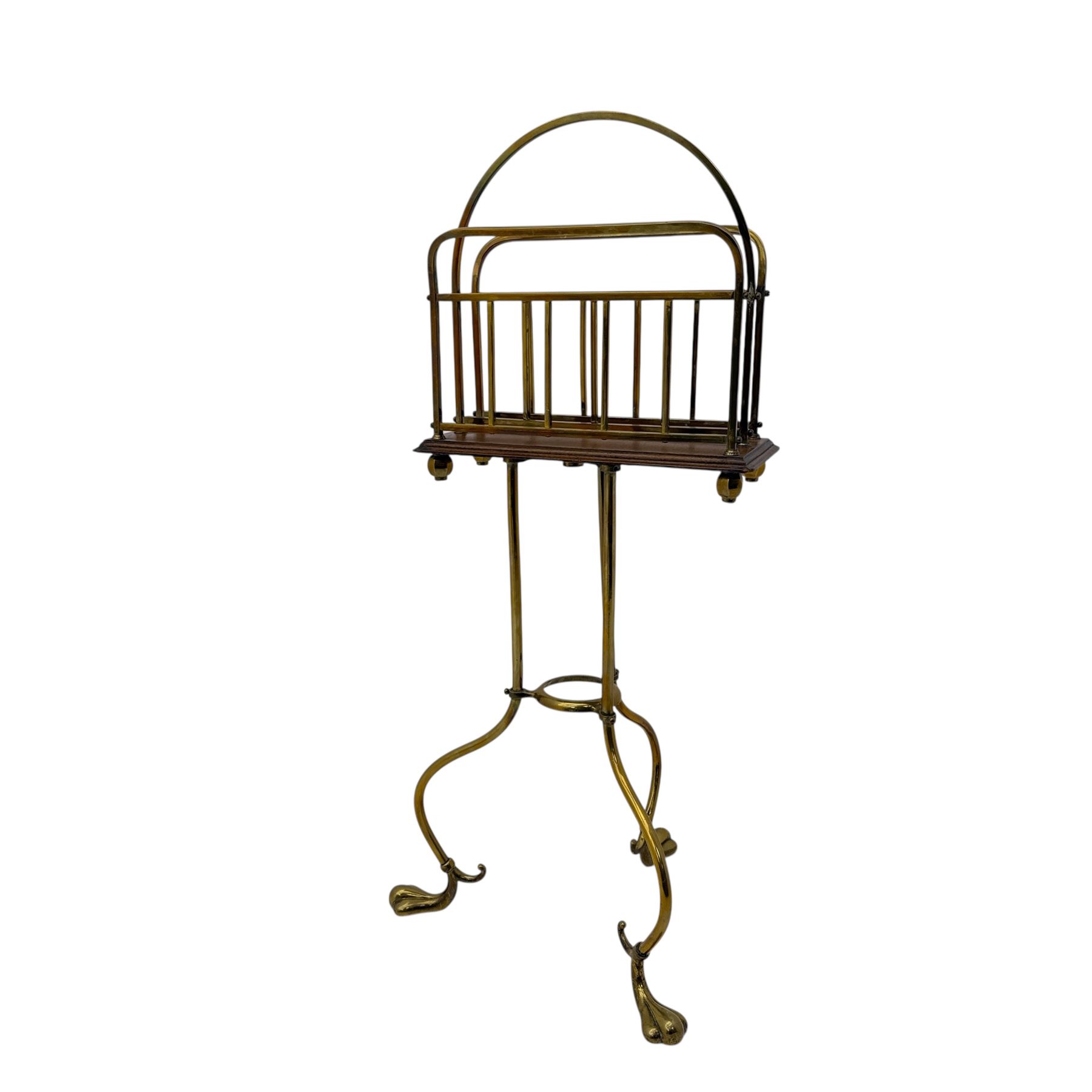Edwardian oak and brass revolving magazine stand, arched frame with slatted slides and oak base, mounted on a brass column supported by three stylized scrolling legs terminating in pad feet