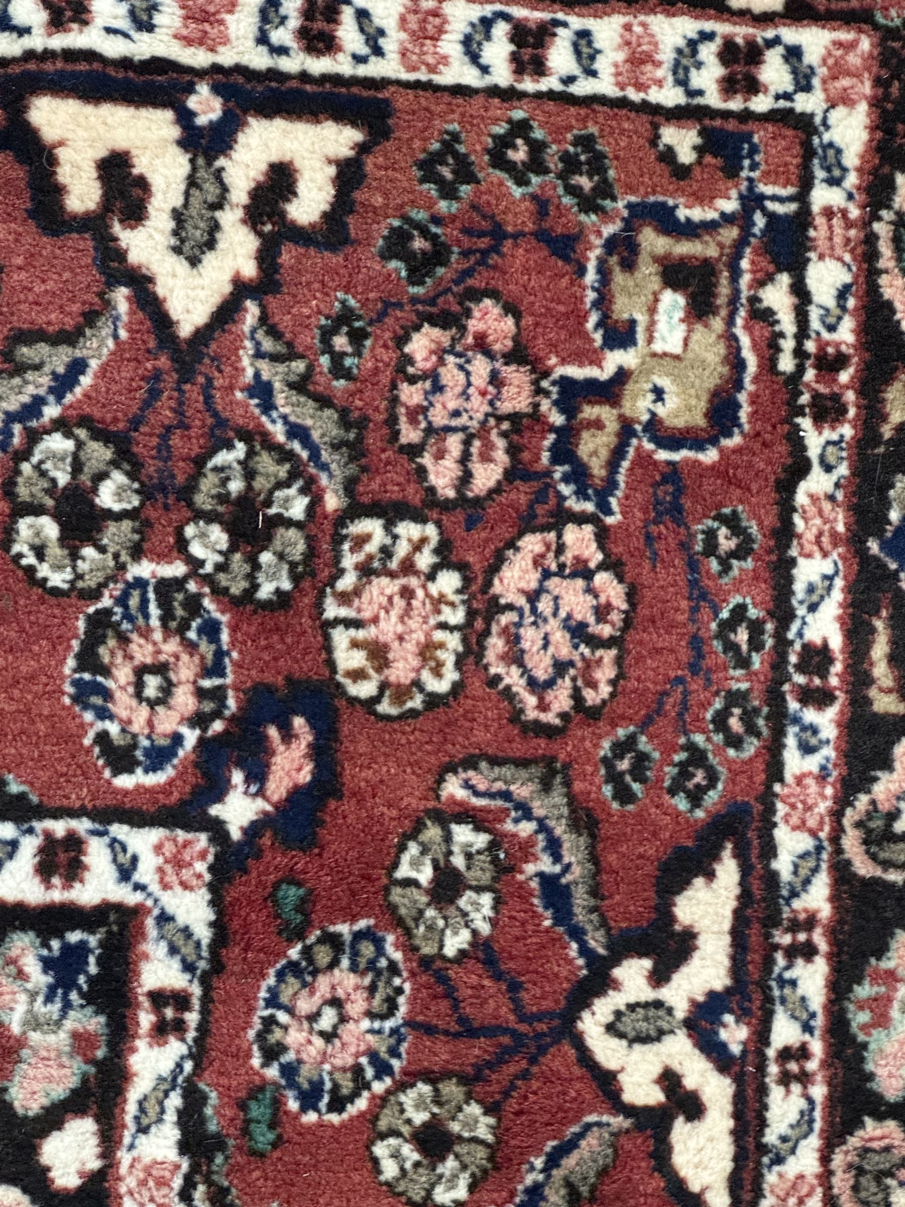 Persian Herati design indigo and red ground carpet, decorated with floral motifs, arched border