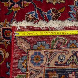 Persian Kashan wool carpet, red field centred with large floral medallion and conforming pendants, decorated with scrolling foliage and flowerheads, indigo spandrels and borders, from the region of Kashan
