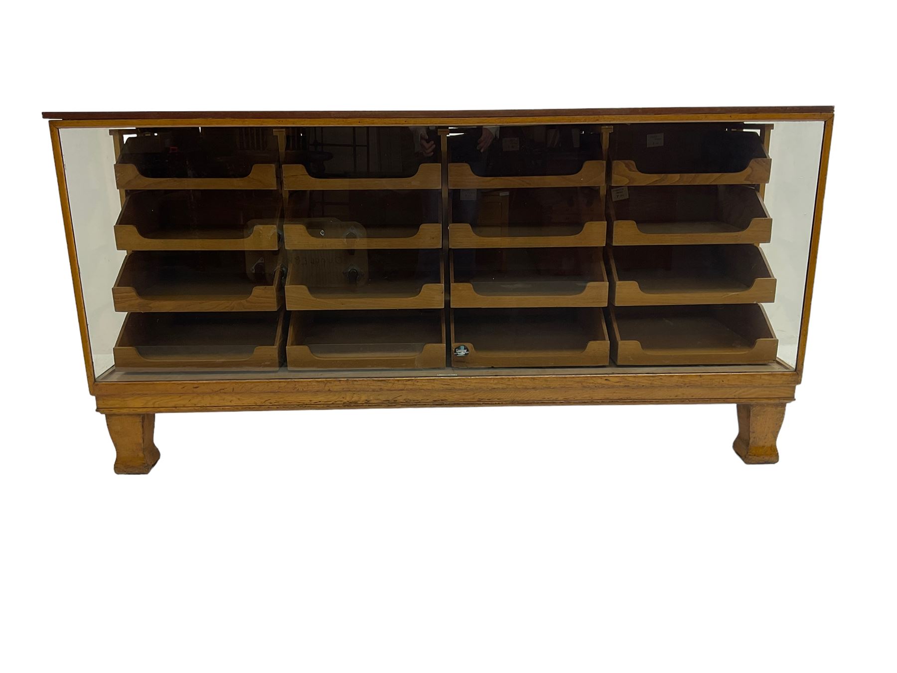 Early 20th century oak framed haberdashery shop counter, veneered top with glazed front and sides, fitted with sixteen graduating drawers with oak fronts and handles, raised on shaped supports
