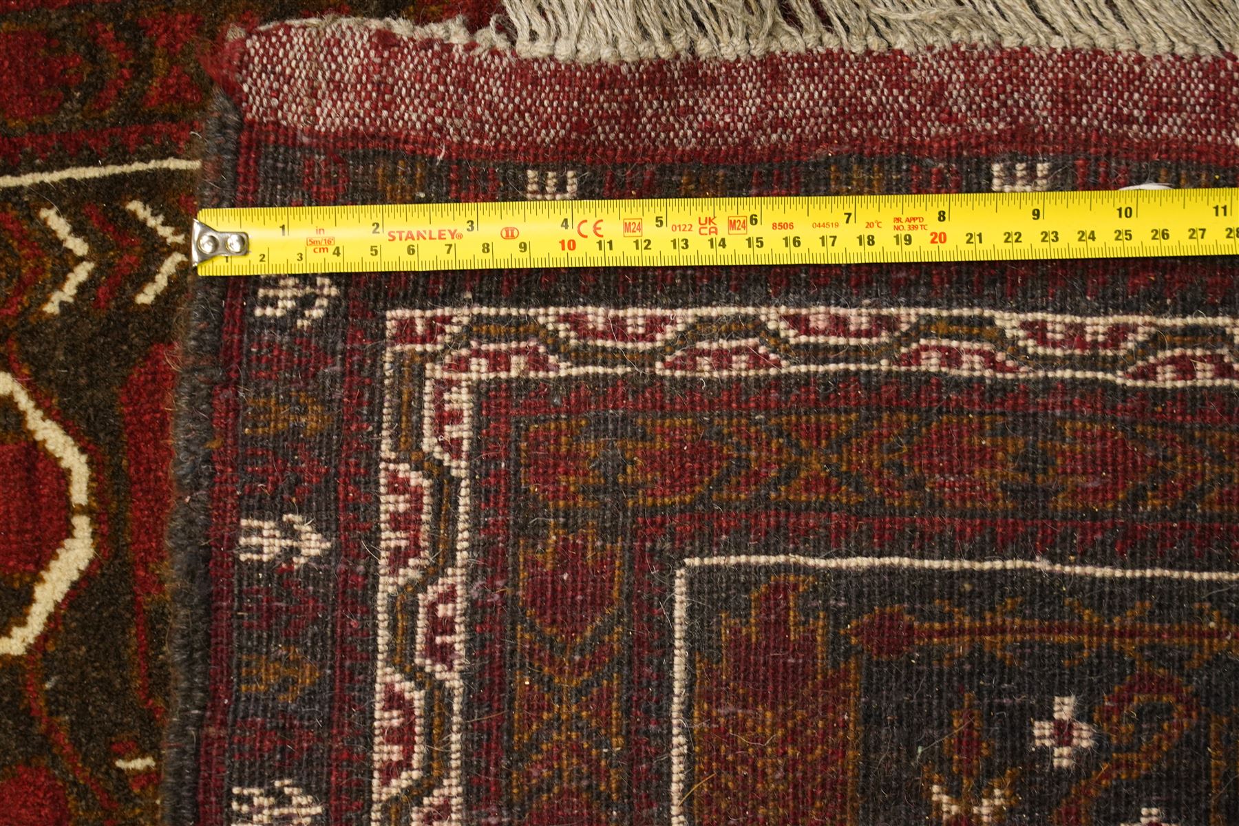 Baluchi hand-knotted prayer rug, dark brown ground divided into six panels decorated with stylised tree-of-life and flowering motifs in madder red and ivory, enclosed by multiple narrow geometric borders, with fringed ends
