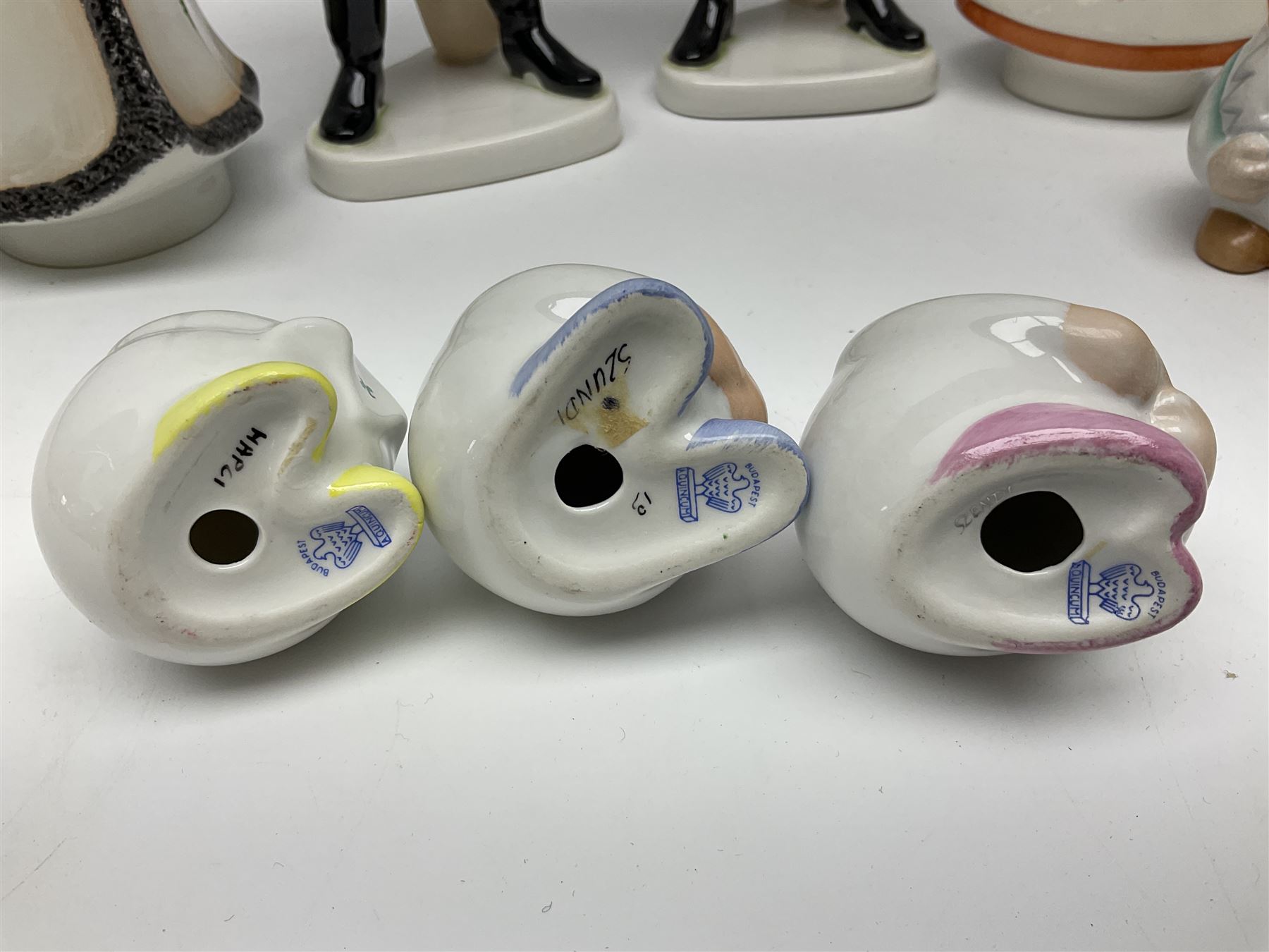 Group of eleven Aquincum of Budapest figures, comprising two of a man in a feather hat, seven dwarves, man and woman in traditional dress, all with printed marks beneath