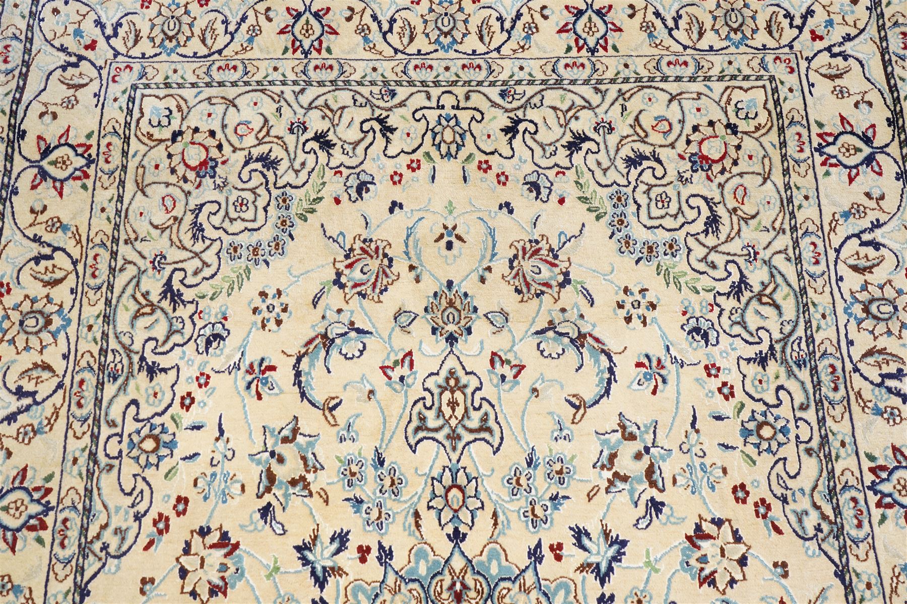 Central Persian Nain hand-knotted silk and wool rug, ivory field with a cusped medallion  issuing radiating pendants, with an all-over design of scrolling arabesques, palmettes and floral sprays, framed main border of meandering vinery and stylized palmettes, flanked by narrow guard stripes, cotton fringe ends  