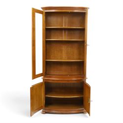 Wesley Barrell - French cherry wood bow front display cabinet, the upper section with glazed doors and three adjustable shelves, raised on cupboard base with brushing slide and further adjustable shelf, raised on a moulded plinth base with bracket feet